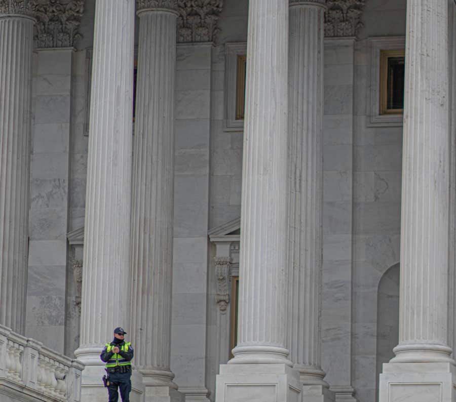 Ein Polizeibeamter, Der Nahe Weißen Betonsäulen Eines Gebäudes Steht